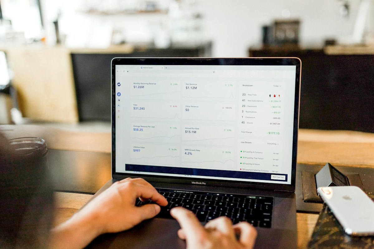 Mains posées sur le clavier d'un ordinateur portable dont l'écran affiche une interface de gestion